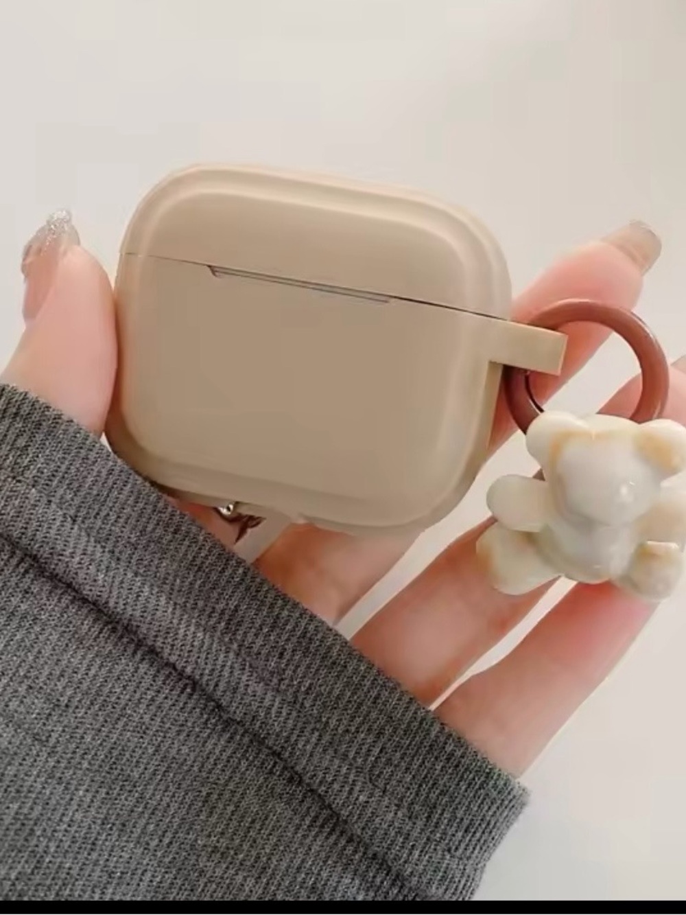 Beige Silicone AirPods Case with Decorative Ring and Charm.